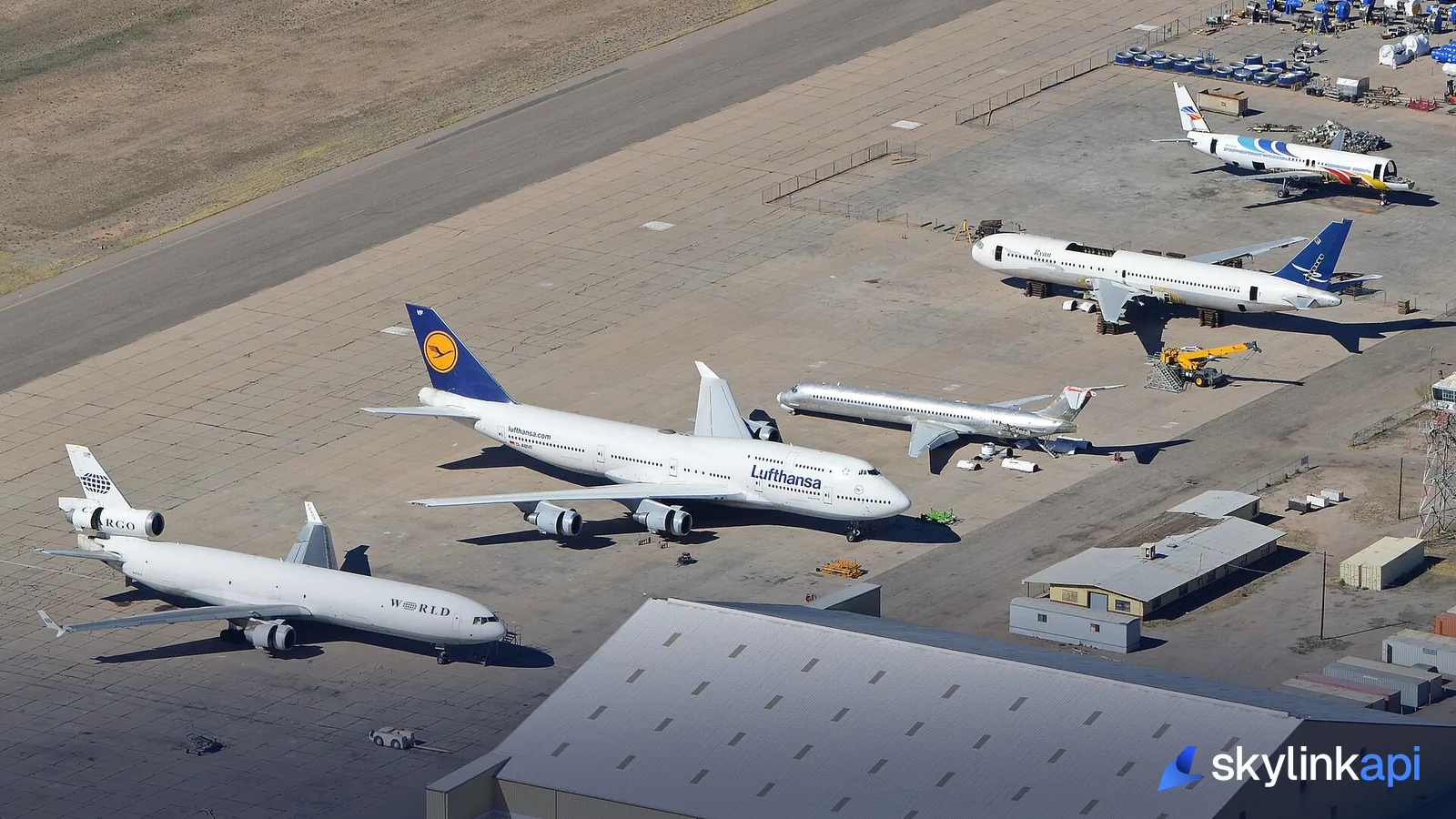 An aerial view of airliners from several different carriers parked on an apron