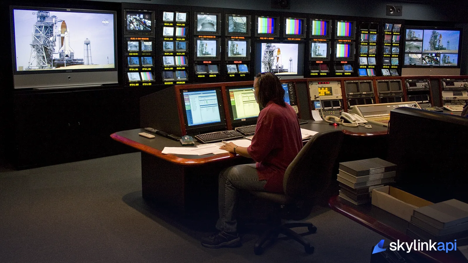 An operator at a desk surrounded by monitoring screens in a control room