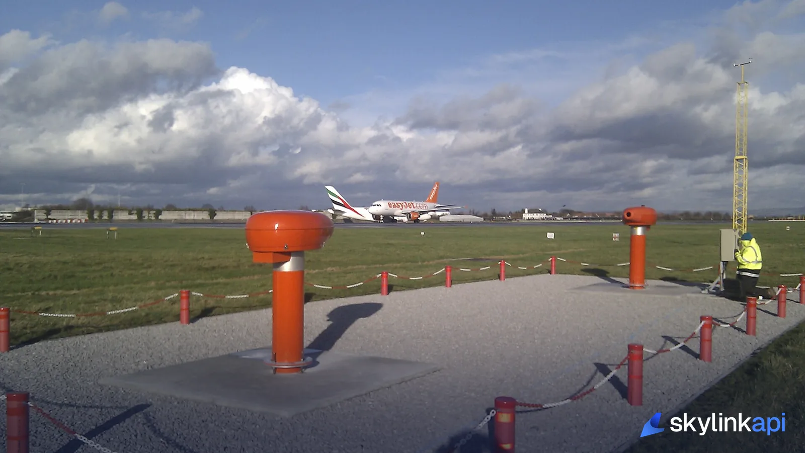 Approach lighting and aircraft at an airfield under a broken cloud deck