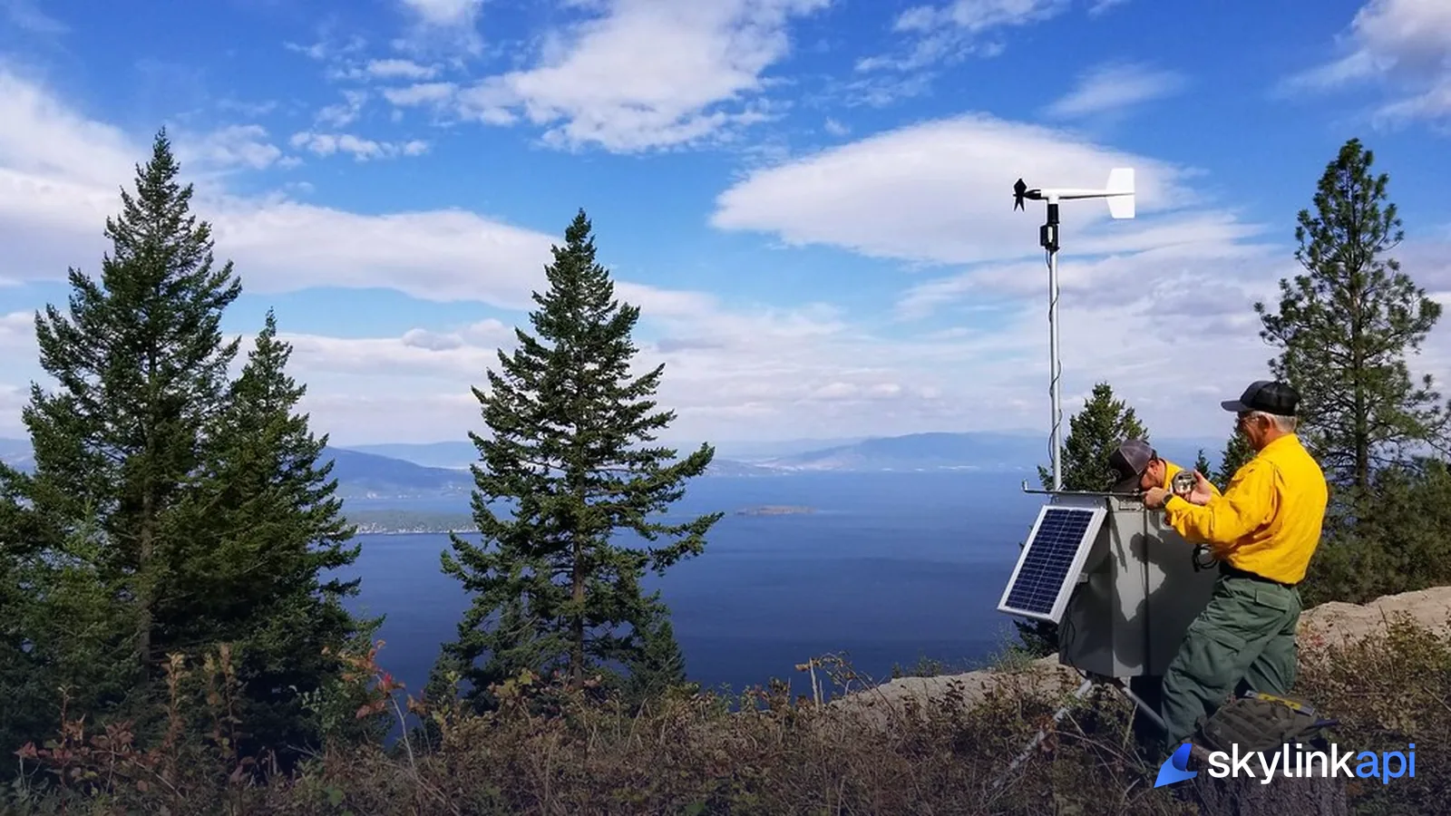 A technician servicing a remote automatic weather station on a hillside