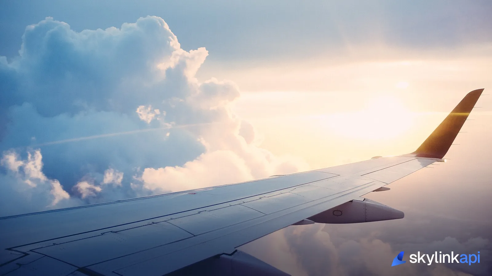 The wing of an airliner above a layer of cloud, seen from the cabin window