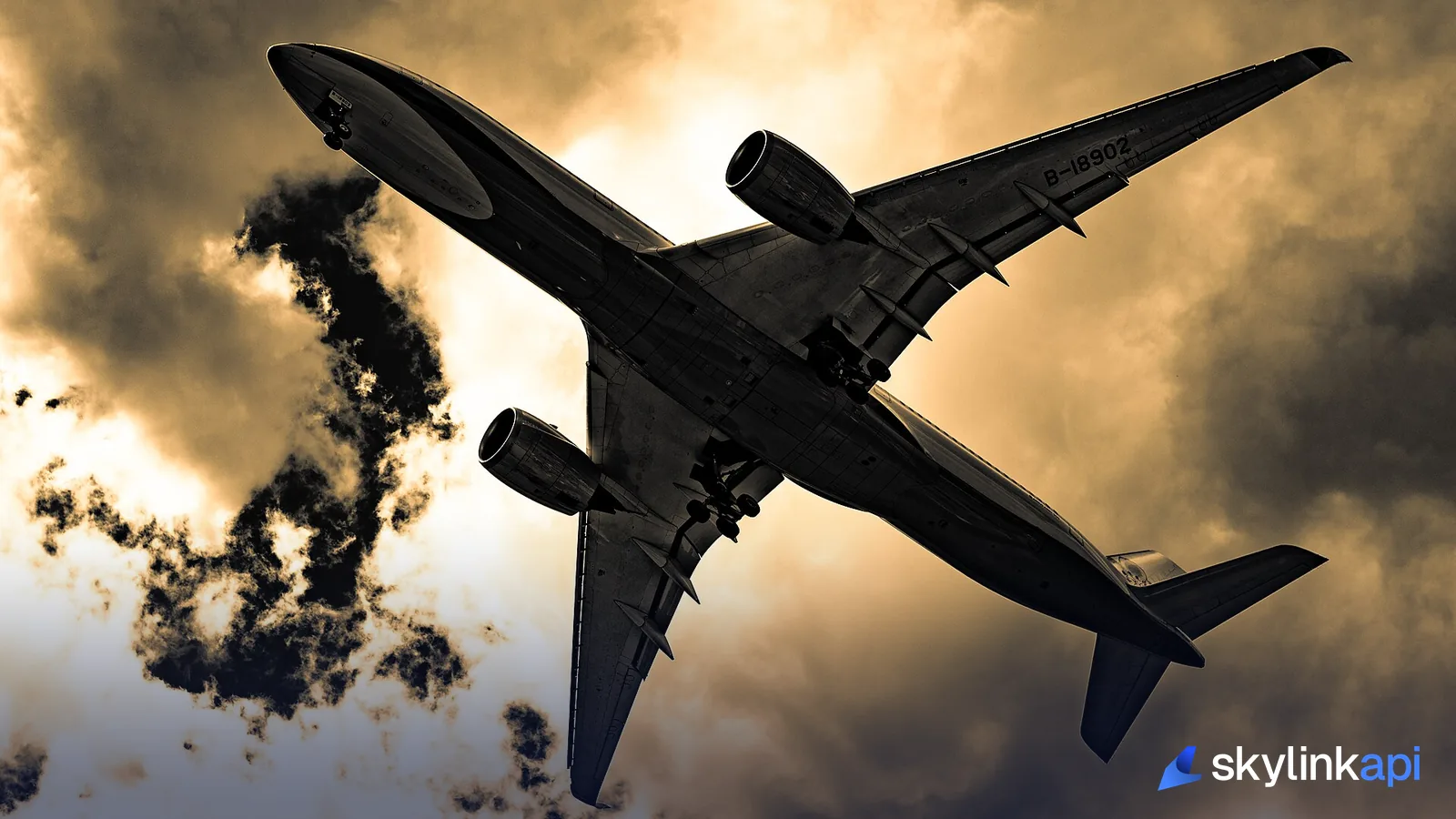 The underside of a wide-body airliner passing low overhead against a dramatic golden sky