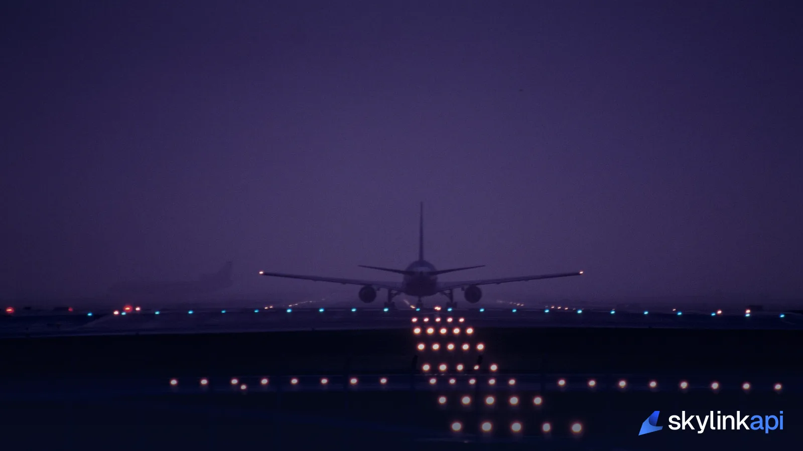 An airliner on the runway at dusk, amid approach and runway lighting