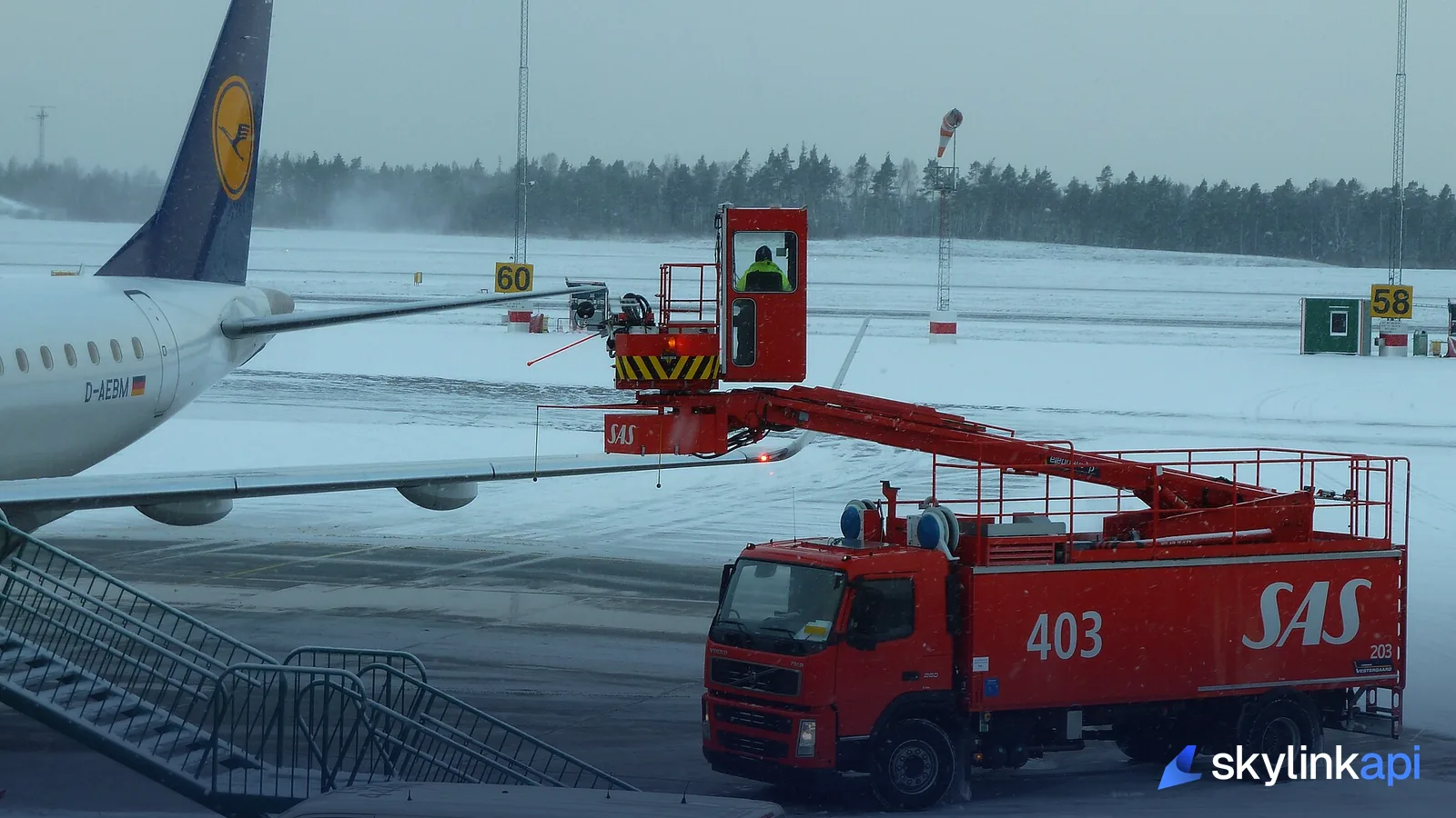 A de-icing truck spraying an aircraft wing on a snowy ramp