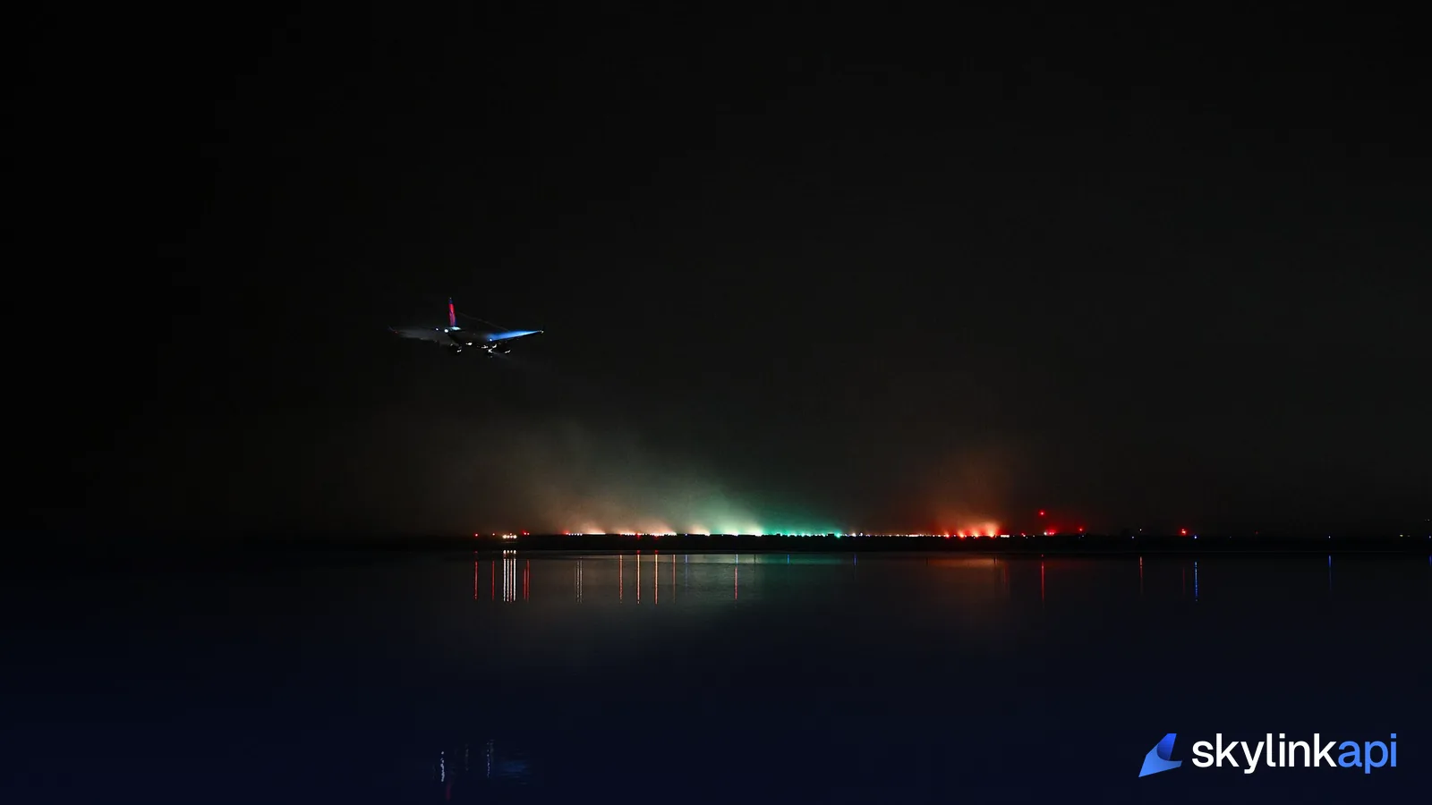 An airliner on approach at night, runway threshold lights glowing through mist