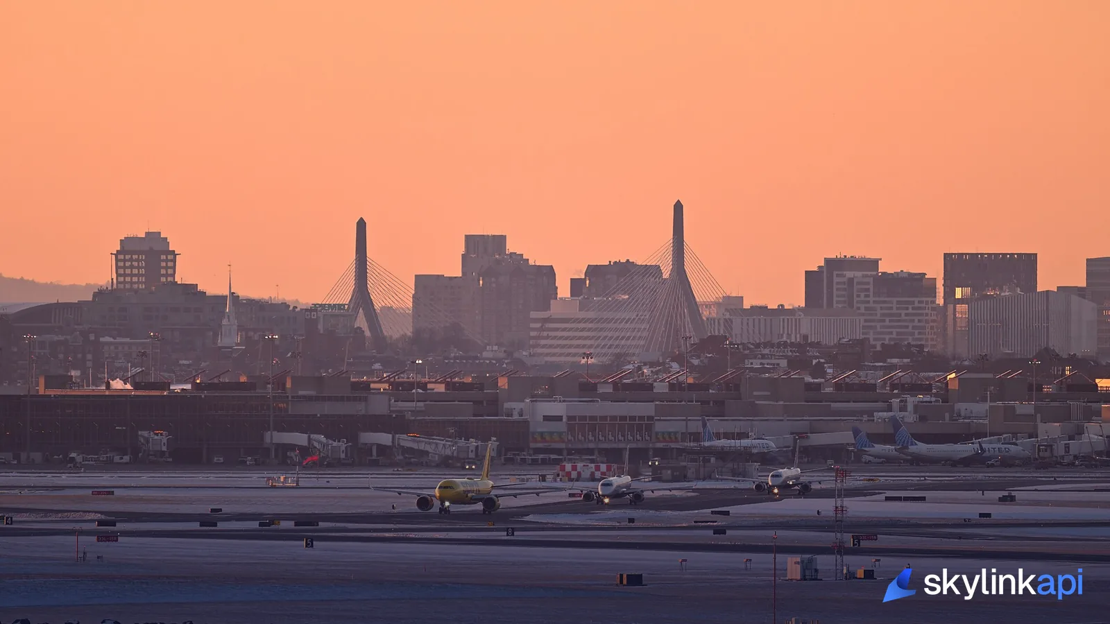 An aircraft taxiing at dusk with the airport's city skyline beyond