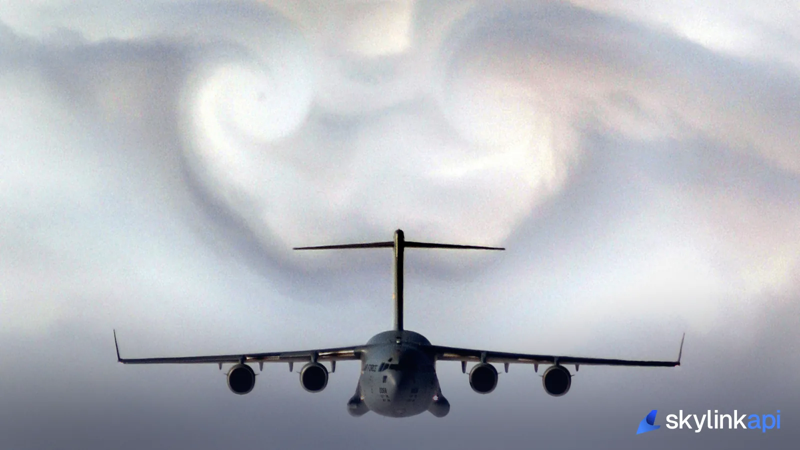 A military transport aircraft flying through swirling, turbulent cloud