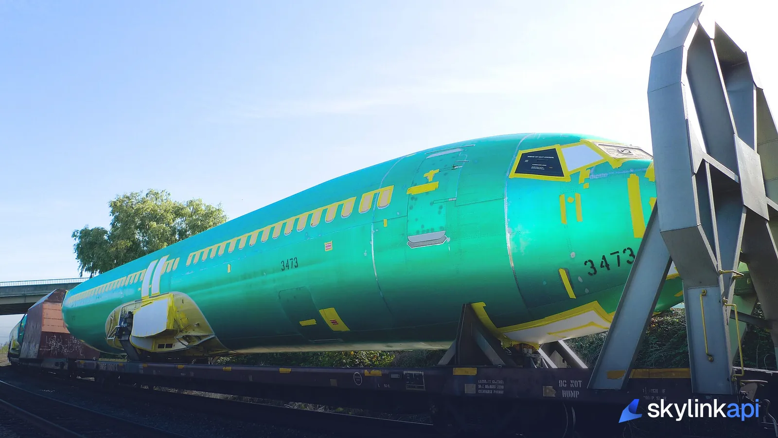 A green-primer Boeing 737 fuselage on a rail car, its manufacturer line number stencilled on the side