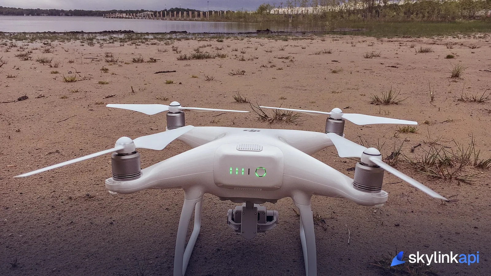 A DJI Phantom quadcopter drone on the ground near a waterfront