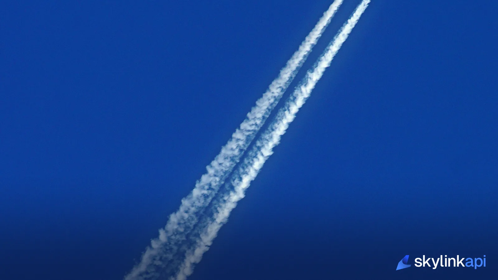 Jet aircraft flying through blue sky leaving a contrail, equipped with ADS-B Out avionics