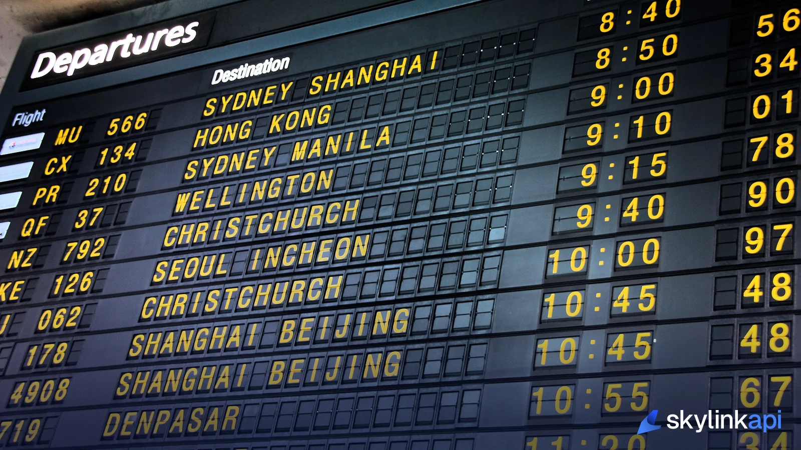 A split-flap departures board listing flight numbers, destinations, and departure times