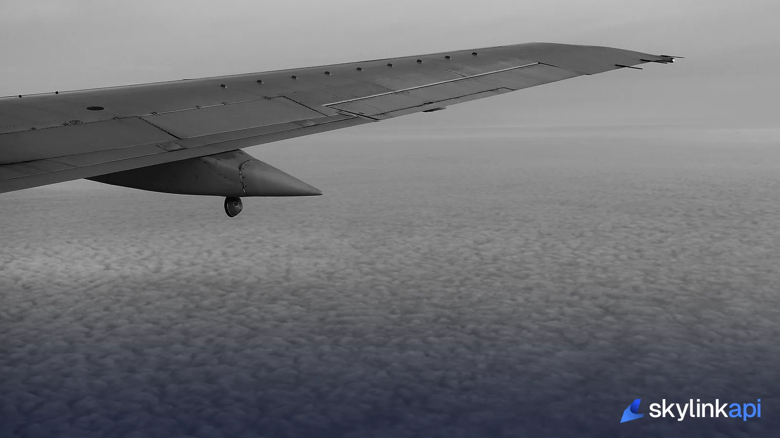 An airliner's wing above a layer of cloud, seen from the cabin window during the wait